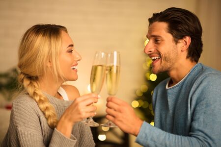 Happy spouses clinking champagne glasses, celebrating holidays together at homeの写真素材