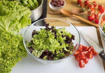 healthy and vegan food concept. Glass bowl with fresh salad on the kitchen tableの写真素材