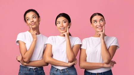 Three Pensive Diverse Girls Thinking Touching Chin Posing Over Pink Studio Background. Womens...