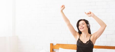 Morning energy. Happy girl dancing in headphones, waking up in morning, panorama with empty space