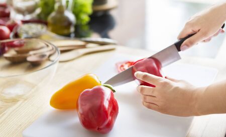 Woman hands cutting red paprika with knife. Woman loves cooking fresh salad for dinner, copy spaceの写真素材