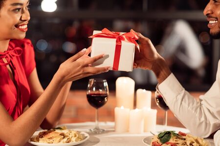Romantic Date. Loving Couple Exchanging Gifts Celebrating Valentine Having Dinner In Restaurant. Croppedの写真素材