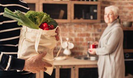 Eco friendly shopping. Senior couple unpacking fabric bag with organic food, panorama