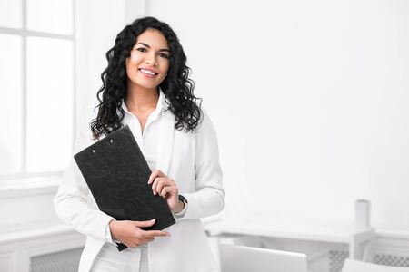 Successful Businesswoman. Portrait of smiling hispanic manager standing with clipboard, looking at...