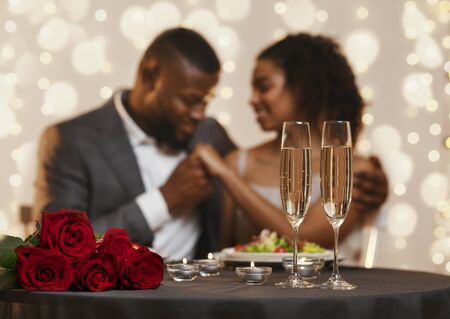 Two glasses of champagne and bunch of red roses over black couple in love, celebrating Valentines Day at restaurantの写真素材