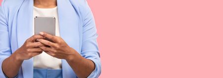 Cool Mobile App. Unrecognizable black girl using smartphone over pink wall. Panorama, copyspaceの写真素材