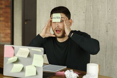 Too Much Work. Shocked Man Touching Face Having Sticky Notes Everywhere Sitting At Laptop In Modern Office. Selective Focusの写真素材