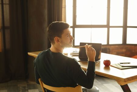 Office Work. Young Entrepreneur Guy Thinking Holding Pencil Working Sitting At Workdesk Indoors. Selective Focusの写真素材