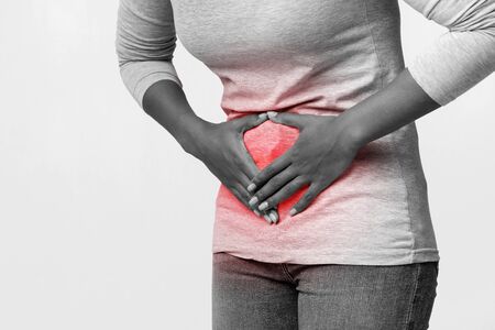 Gynecologycal problems. Cropped of afro woman rubbing her belly, having acute pain, monochrome,...