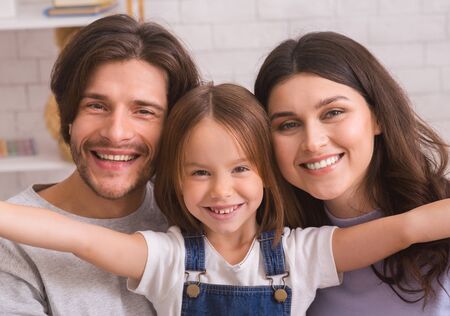 Family selfie. Adorable little girl taking photo with her parents at home, enjoying spending time together, closeupの写真素材