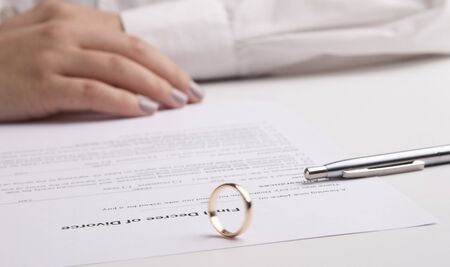 Woman signing divorce decree, wedding ring lying on document, panorama, copy spaceの写真素材