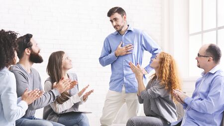 Young man appreciating support of group members at therapy session in rehab, grateful for...