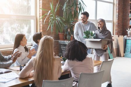 Friendly young multiracial business team welcoming girl in hijab new employee, manager introducing...