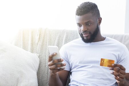 Mobile banking. African american man cheking his credit card balance with application, empty space