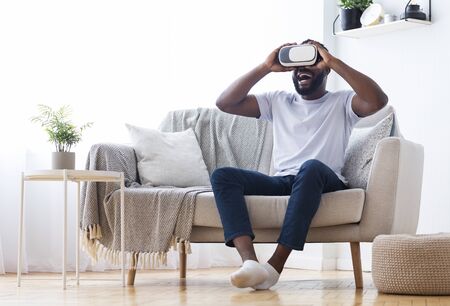 Millennial african man enjoying virtual reality glasses at home, empty spaceの写真素材