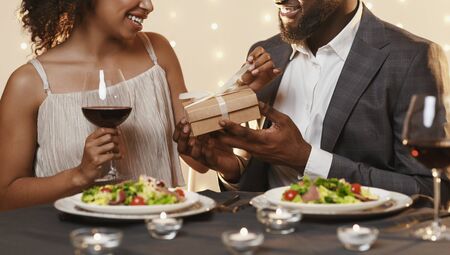 Afro man in love giving valentine's present to his girlfriend, cropped, panoramaの写真素材