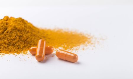 Pile of turmeric capsules and powder on white background, panorama, copy space. Healthy concept