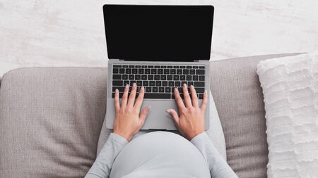 Unrecognizable Pregnant Girl Using Laptop Browsing Internet Sitting On Sofa Indoors. Panorama, Mockup, Top-Viewの写真素材