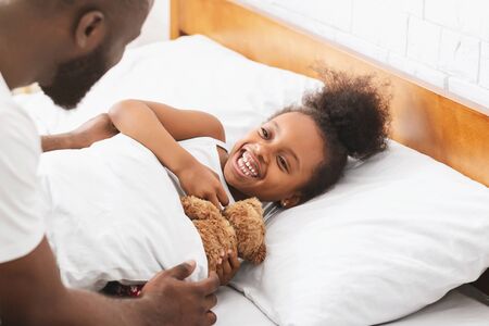 Cute black little girl happy to see her dad in the morning, just woke up, close upの写真素材