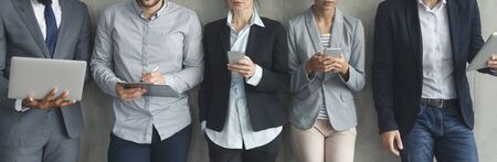 Businesspeople with phones and laptops over grey wall, panorama