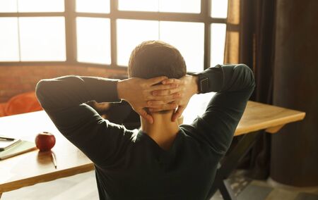 Relax At Work. Unrecognizable Young Man Sitting Holding Hands Behind Head Resting At Workplace...