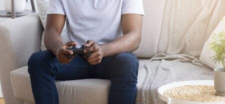 African guy playing video games with joystick at home, panorama, empty space
