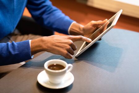 Reading News. Unrecognizable afro guy holding digital tablet device computer at coffee shop, copyspaceの写真素材
