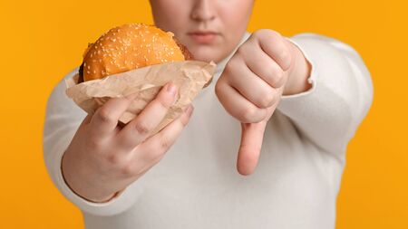 Artificial Flavors In Fast Food Concept. Unrecognizable Overweight Woman Holding Burger And Showing...