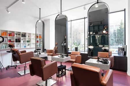 Modern beauty salon with places for makeup artist and hairdresser, big stylish mirrors, pink interior, no peopleの写真素材