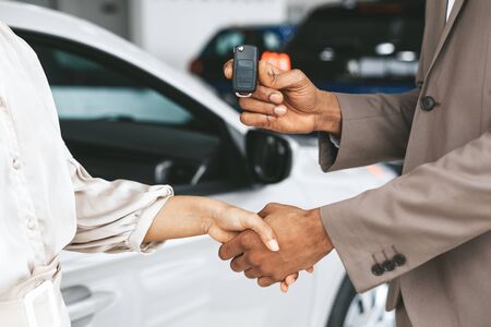 Car Sales. Unrecognizable Seller Greeting Lady Buyer With Handshake And Giving Key Standing Near...