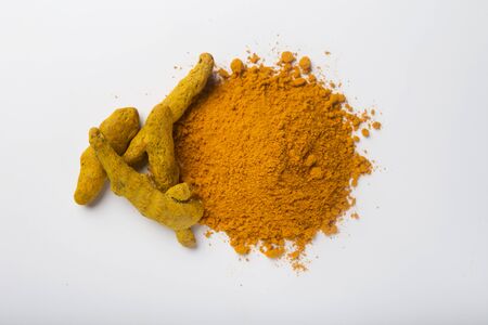 Turmeric powder pile with curcuma sticks isolated on white background