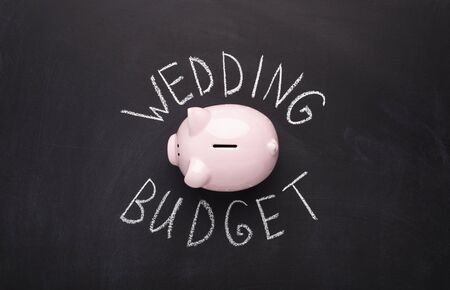 Many coins in a piggy box with wedding budget text on black background. Wedding concept. saving conceptの写真素材
