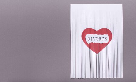 Break up and dissolution concept. Cut paper heart with divorce text, on gray background, copy spaceの写真素材