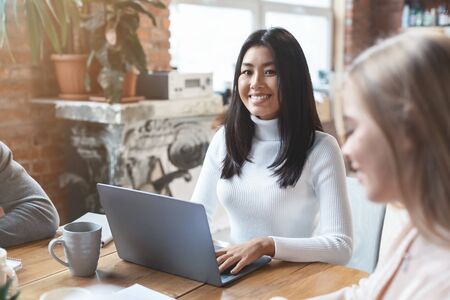 Portrait of pretty smiling asian girl having business meeting with colleagues in office