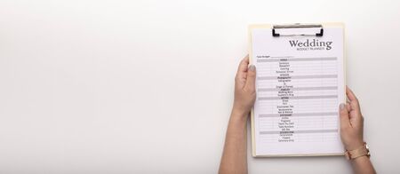 Bride holding wedding planning checklist with items on clipboard, wide panorama, copy space