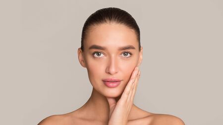 Facial treatment. Woman with perfect skin looking at camera on grey background, panoramaの写真素材