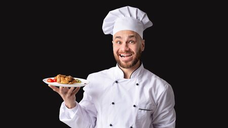 Joyful Chef Man Holding Plate With Chicken Dish Posing Over Black Background. Studio Shot, Panorama