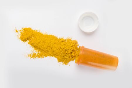 Curcuma medicine from turmeric roots and powder in jar. Anti cancer medicine. White table, Top view.の写真素材