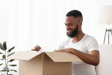 Online Store and home delivery. Excited afro american man get a package, free space