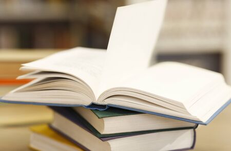 Library Lovers Month. Side view of opened manual with blank pages lying on a stack of books on wood...