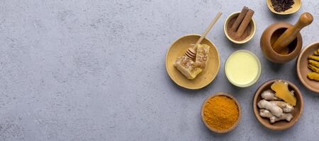 Ingredients for hot ayurvedic drink. Turmeric powder, curcuma root, cinnamon, cinnamon, honey over grey backgroundの写真素材