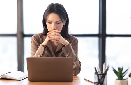 Concentrated Worker. Portrait of young focused woman using laptop thinking about new project, copyspaceの写真素材