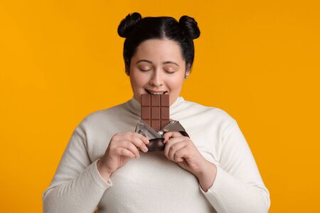 Chocoholic Concept. Young Plus Size Girl Enjoying Eating Chocolate Bar, Standing With Closed Eyes On...