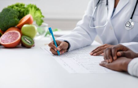 Cropped of afro woman nutritionist making treatment plan for patient at clinic, copy spaceの写真素材