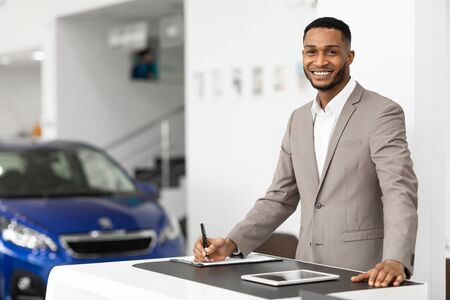 Car Sales Manager Working Selling Automobiles Standing At Desk In Luxury Dealership Office. Selective Focus, Copy Spaceの写真素材