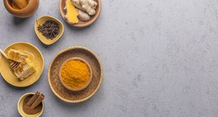 Herb drink concept. Healthy food made from turmeric roots, exotic spices with honey on gray background, panorama, copy spaceの写真素材