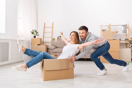 Young couple having fun while moving to a new apartment. Happy people in the new house, copy space
