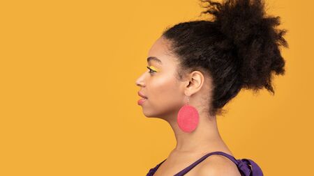 Profile Portrait Of Serious Black Woman Posing Over Orange Background, Looking At Copyspace, Studio...