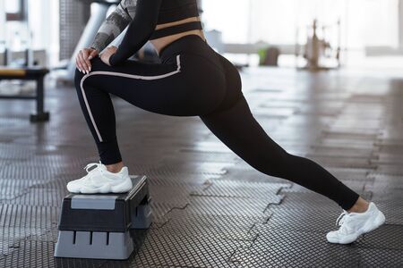 Young woman stretching on step platform in sports club, closeupの写真素材