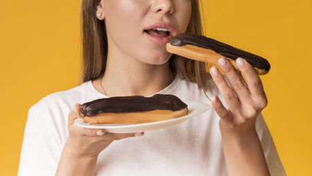 Sugar Craving. Unrecognizable Girl Eating Tasty Eclairs With Chocolate Cream, Enjoying Unhealthy...
